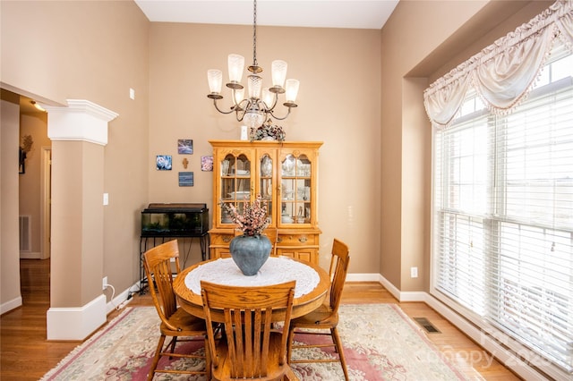 dining space featuring hardwood / wood-style floors, decorative columns, and a chandelier