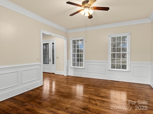 empty room with crown molding, dark wood-type flooring, and ceiling fan