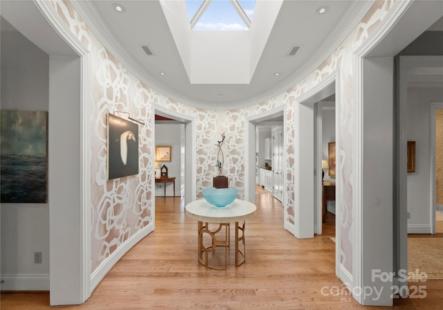 corridor featuring ornamental molding, a skylight, and light wood-type flooring