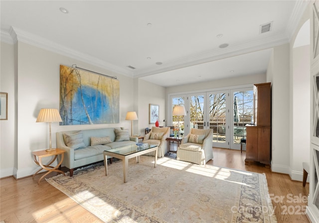 living room with crown molding, light hardwood / wood-style floors, and french doors