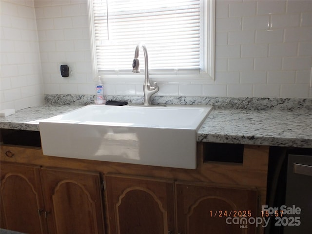 details featuring tasteful backsplash, light stone countertops, and sink