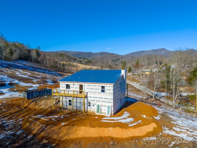 snow covered house featuring a deck with mountain view