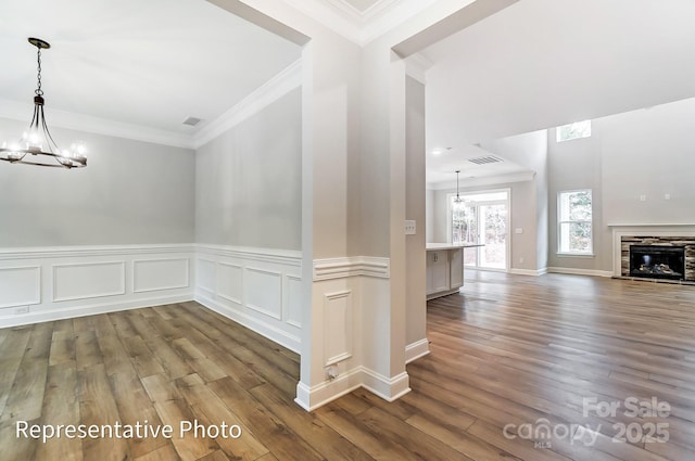 unfurnished dining area with a stone fireplace, dark wood-type flooring, visible vents, and a notable chandelier