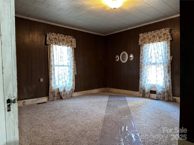 spare room with ornamental molding, carpet flooring, and wooden walls