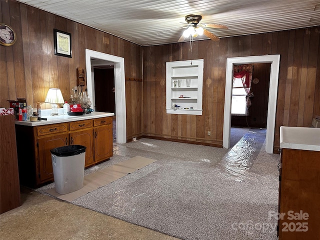 interior space with built in shelves, wooden ceiling, ceiling fan, and wood walls