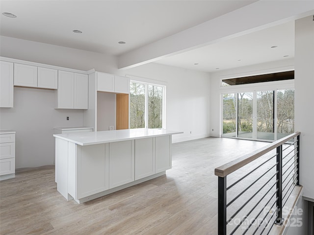 kitchen with light hardwood / wood-style floors, a kitchen island, and white cabinets