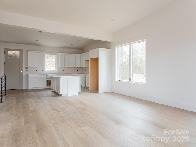 kitchen featuring white cabinetry, light hardwood / wood-style floors, a center island, and a healthy amount of sunlight