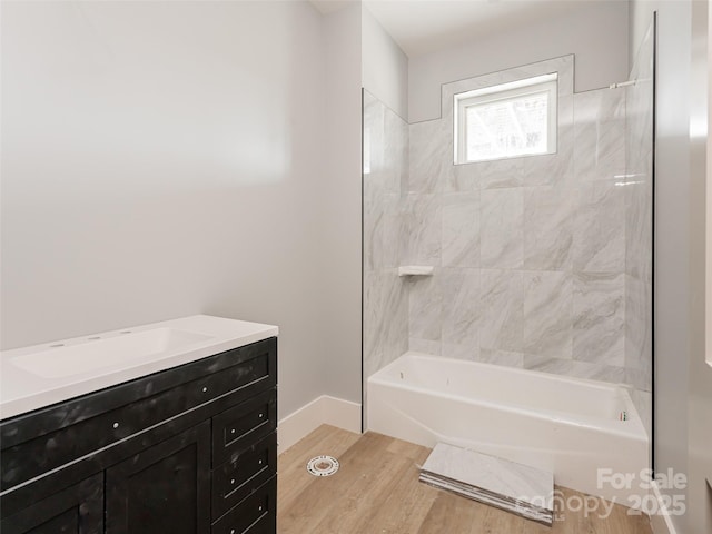 bathroom featuring wood-type flooring, vanity, and tiled shower / bath