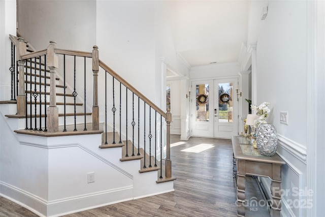 entrance foyer featuring ornamental molding, french doors, dark wood-style flooring, and a decorative wall