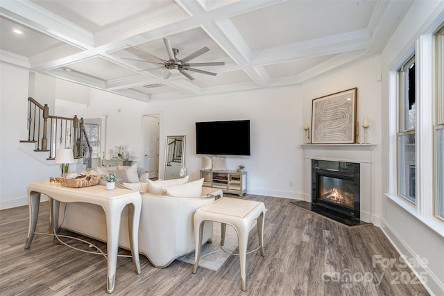 living area featuring wood finished floors, stairway, a glass covered fireplace, and baseboards