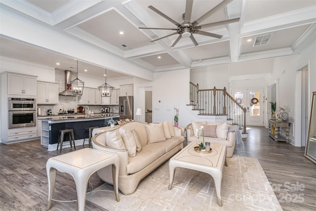 living room featuring stairs, visible vents, coffered ceiling, and beam ceiling