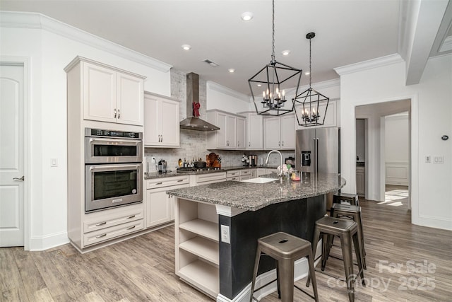 kitchen featuring open shelves, white cabinetry, a kitchen island with sink, dark stone counters, and wall chimney exhaust hood