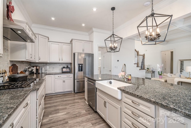 kitchen featuring a sink, white cabinetry, appliances with stainless steel finishes, dark stone countertops, and pendant lighting