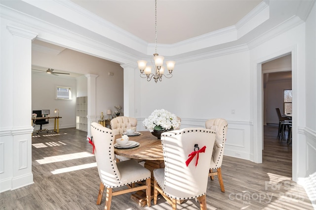 dining area featuring a decorative wall, a wainscoted wall, wood finished floors, decorative columns, and crown molding