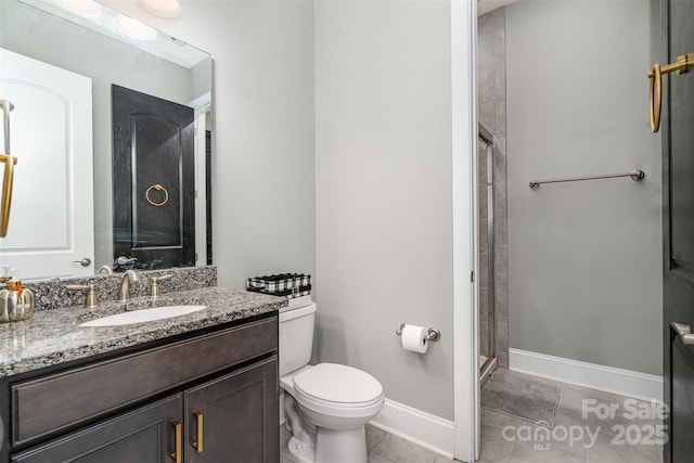 full bathroom with tile patterned flooring, toilet, vanity, baseboards, and a tile shower