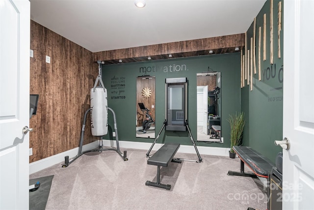 exercise room featuring wooden walls and carpet flooring