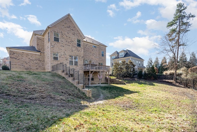 back of house with brick siding, a lawn, and fence