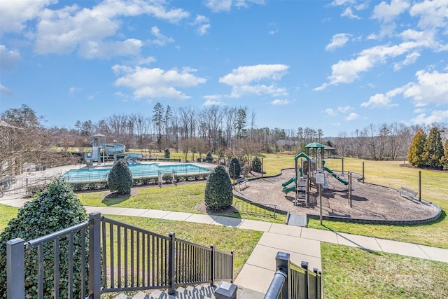 community jungle gym featuring a yard, fence, and a community pool