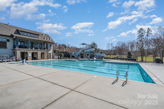 pool with fence, a water slide, and a patio