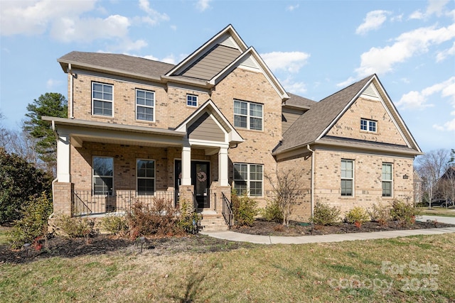 craftsman-style home with a porch, brick siding, a shingled roof, and a front lawn