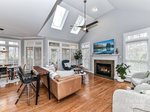 living room featuring high vaulted ceiling, wood-type flooring, a tile fireplace, and a healthy amount of sunlight