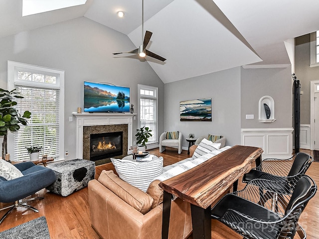 living room with hardwood / wood-style flooring, ceiling fan, a high end fireplace, and a wealth of natural light