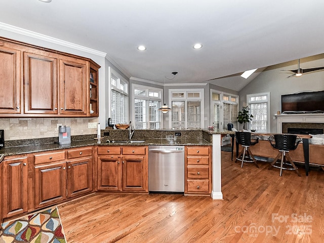 kitchen with dishwasher, sink, dark stone countertops, and light hardwood / wood-style floors