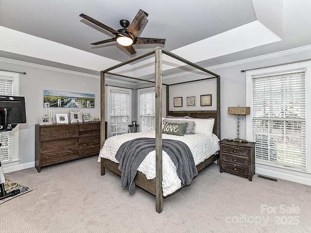 carpeted bedroom with ceiling fan, ornamental molding, and a raised ceiling