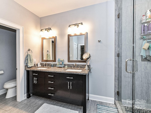 bathroom featuring a shower with door, vanity, hardwood / wood-style floors, and toilet