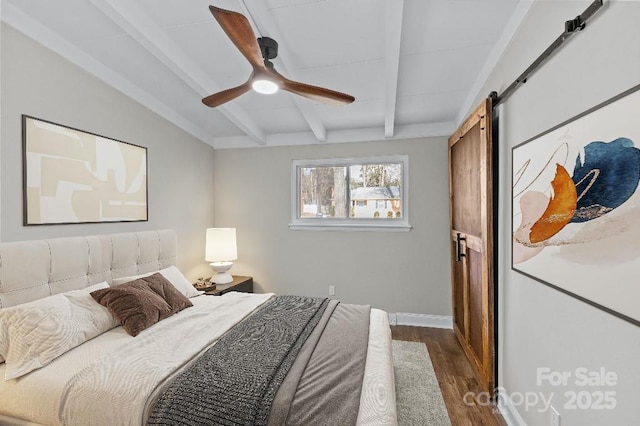 bedroom featuring beamed ceiling, ceiling fan, dark hardwood / wood-style flooring, and a barn door