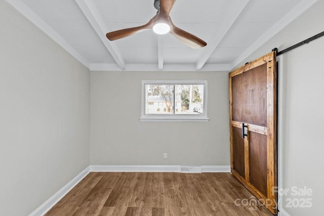 interior space featuring hardwood / wood-style flooring, ceiling fan, a barn door, and lofted ceiling with beams