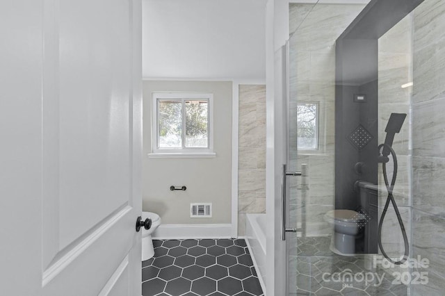 bathroom featuring tiled shower and toilet