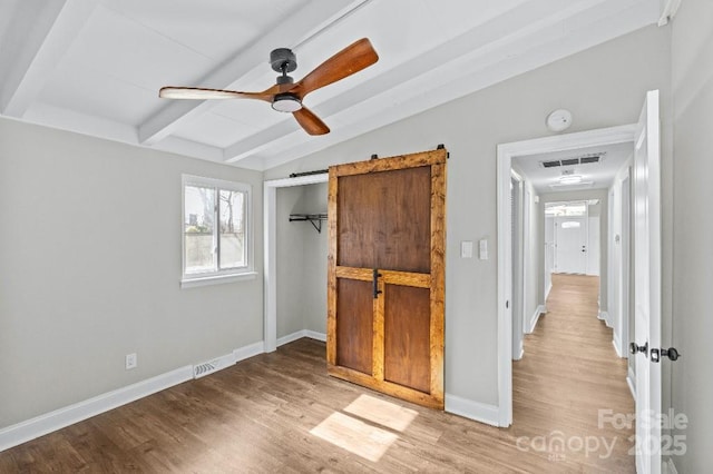 unfurnished bedroom with vaulted ceiling with beams, ceiling fan, and light wood-type flooring