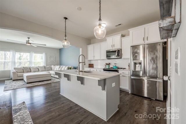 kitchen with sink, a breakfast bar, appliances with stainless steel finishes, white cabinets, and decorative light fixtures