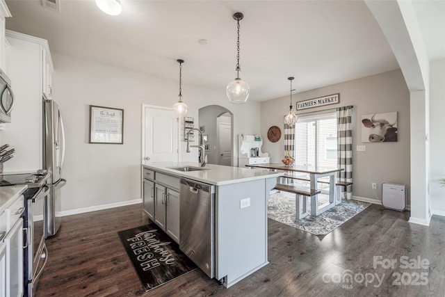 kitchen with decorative light fixtures, an island with sink, white cabinetry, dark hardwood / wood-style flooring, and stainless steel appliances