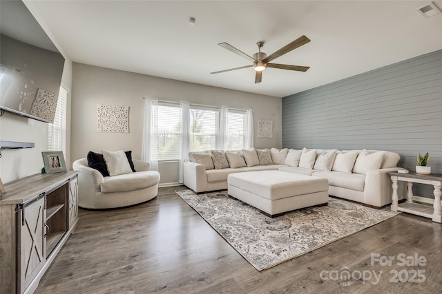 living room with ceiling fan, dark hardwood / wood-style flooring, and wood walls