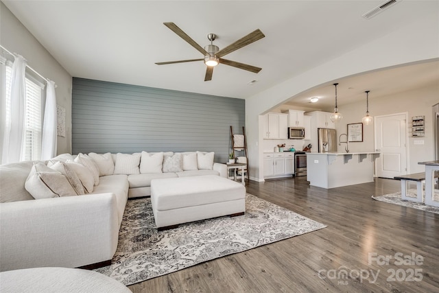 living room with sink, dark wood-type flooring, and ceiling fan