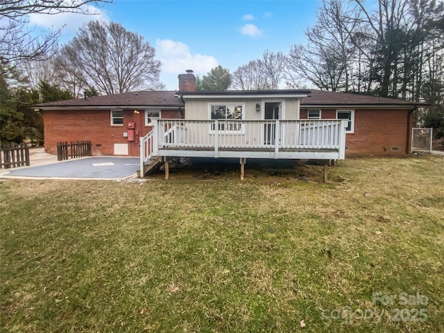 rear view of house with a wooden deck, a yard, and a patio