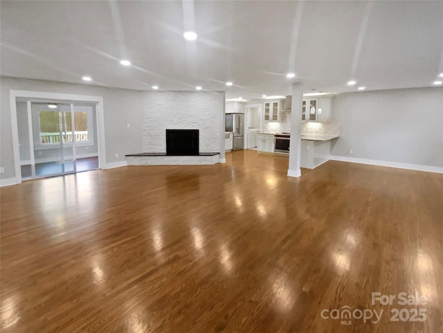 unfurnished living room featuring dark wood-type flooring and a fireplace