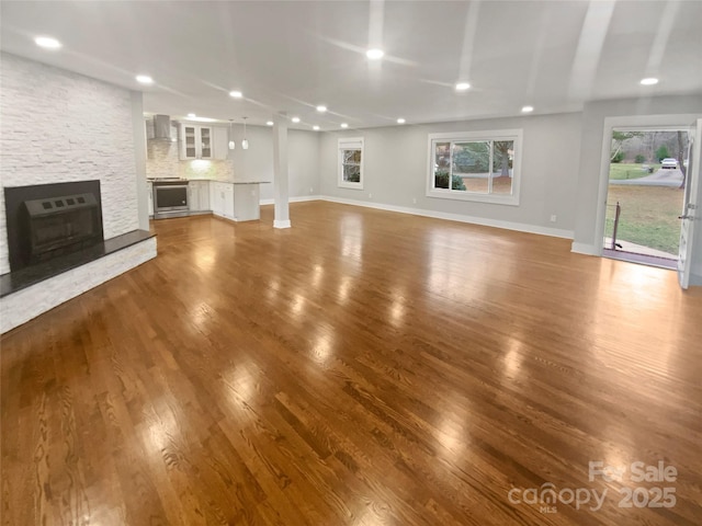 unfurnished living room with wood-type flooring, heating unit, and a fireplace