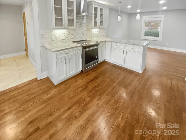 kitchen with white cabinetry, wall chimney exhaust hood, tasteful backsplash, and electric range