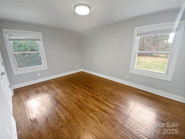 empty room featuring plenty of natural light and dark wood-type flooring