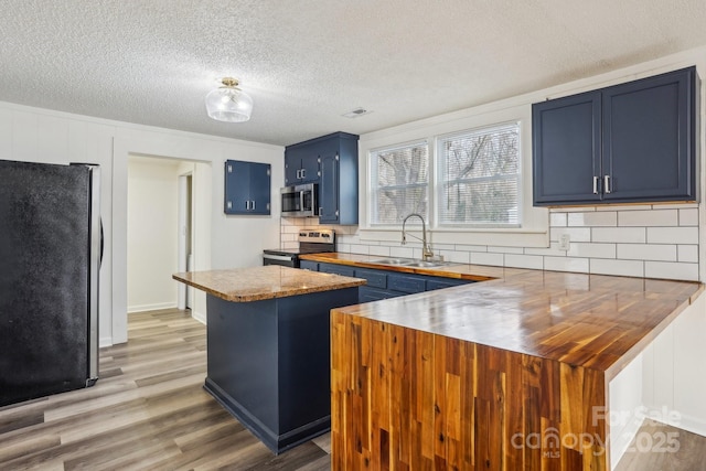 kitchen featuring blue cabinets, butcher block counters, sink, a center island, and stainless steel appliances