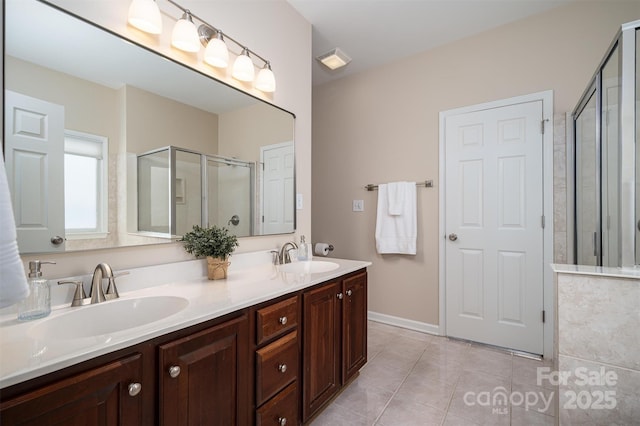 bathroom featuring visible vents, double vanity, a sink, a shower stall, and tile patterned floors