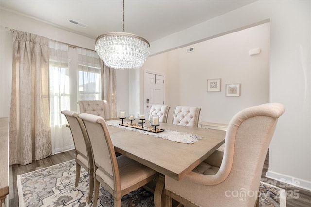 dining space featuring hardwood / wood-style flooring and an inviting chandelier