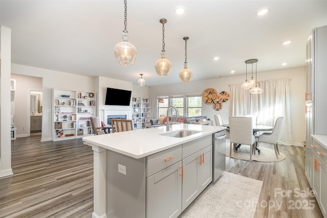 kitchen with dishwasher, sink, a center island with sink, and gray cabinetry