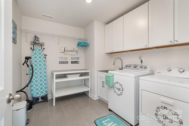 clothes washing area featuring sink, light tile patterned floors, washer and clothes dryer, and cabinets