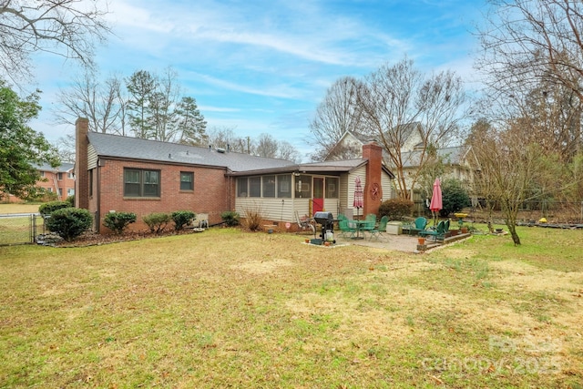 rear view of house with a sunroom, a yard, and a patio area