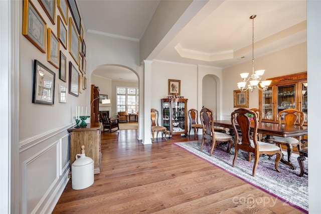 dining space with ornamental molding, wood-type flooring, a tray ceiling, and a chandelier