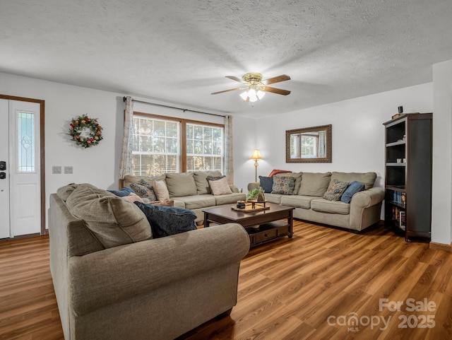 living room featuring ceiling fan, hardwood / wood-style floors, and a textured ceiling